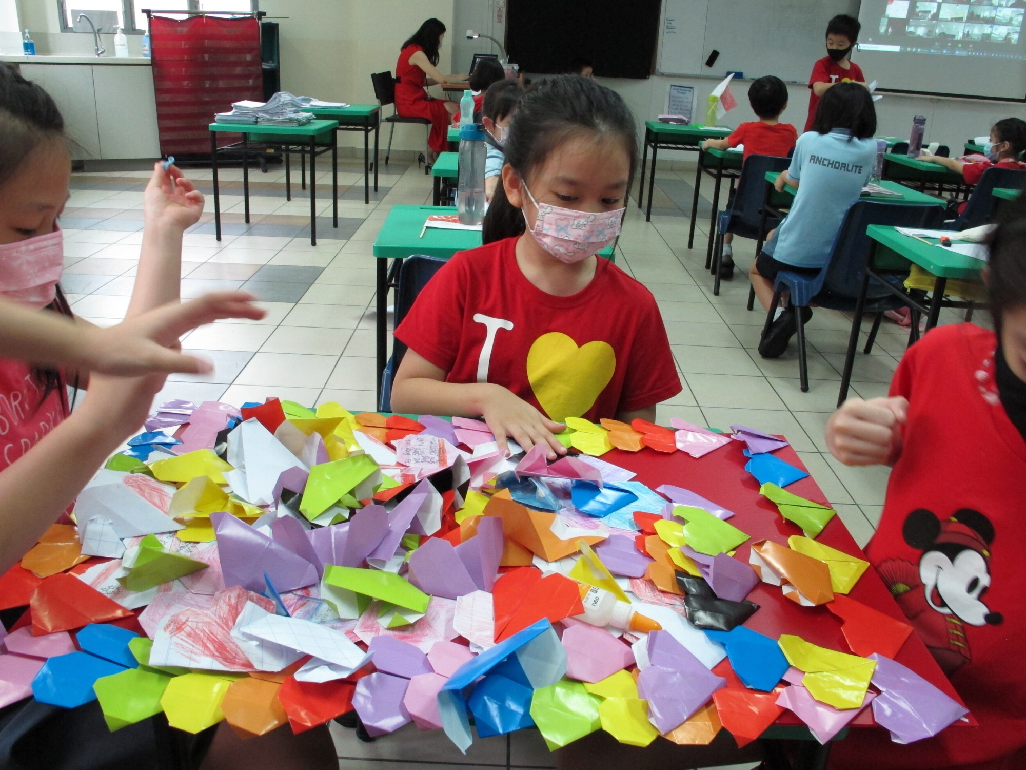 Students folding origami hearts and creating their gratitude board