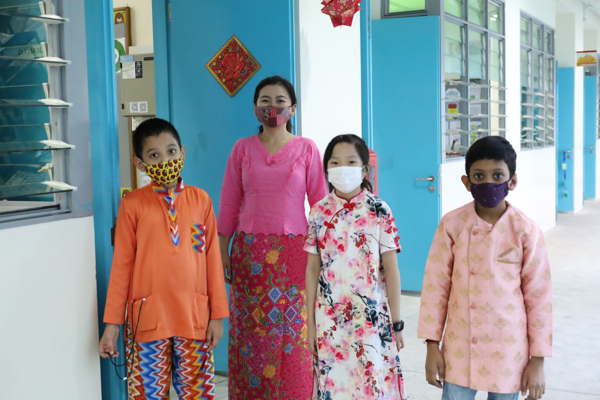 Ms Loy and students adorned in their colourful traditional costumes
